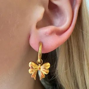 Close-up of Gold Bow Hoop Earrings showing smooth ribbon bow detail and gold-plated finish.