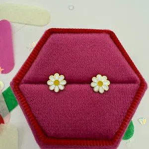 Close-up of Tiny White Daisy Stud Earrings showing white enamel petals and gold center.