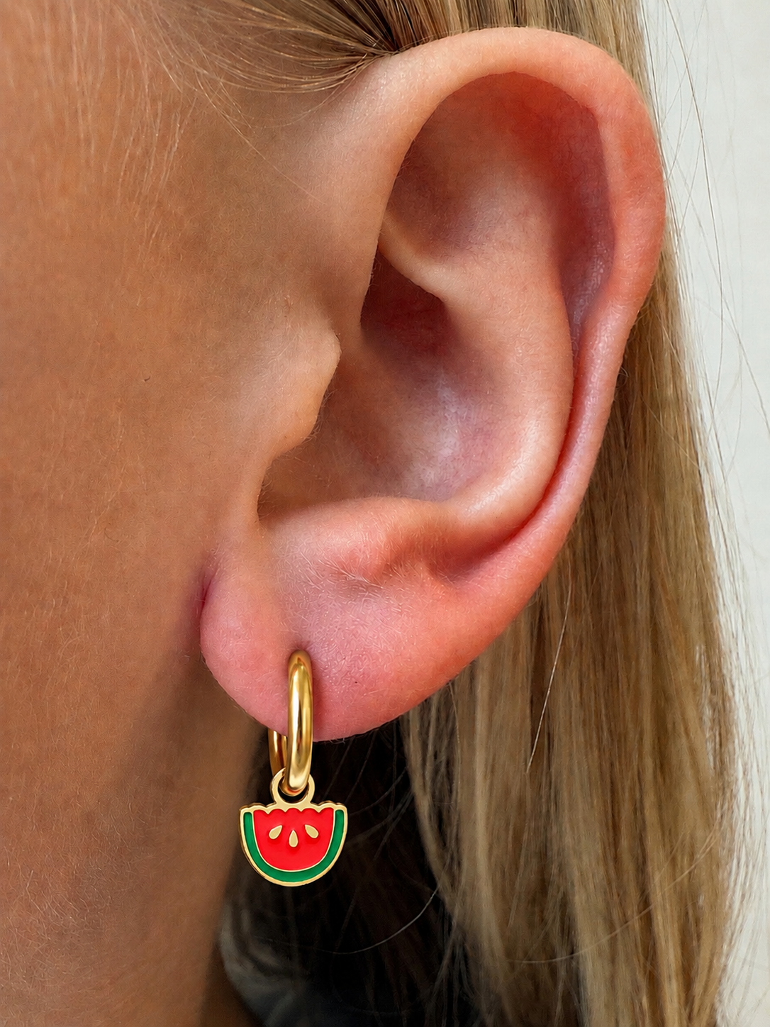 Scalloped Watermelon Charm on gold hoop shown in a little girl’s ear for size and fit reference.