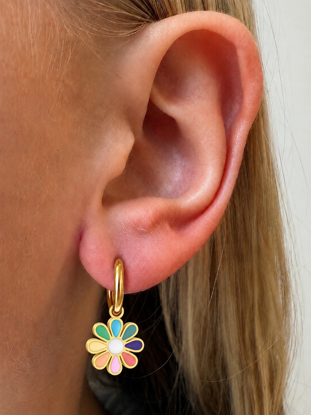 Rainbow Flower Charm on gold hoop shown in a little girl’s ear for size and fit reference.